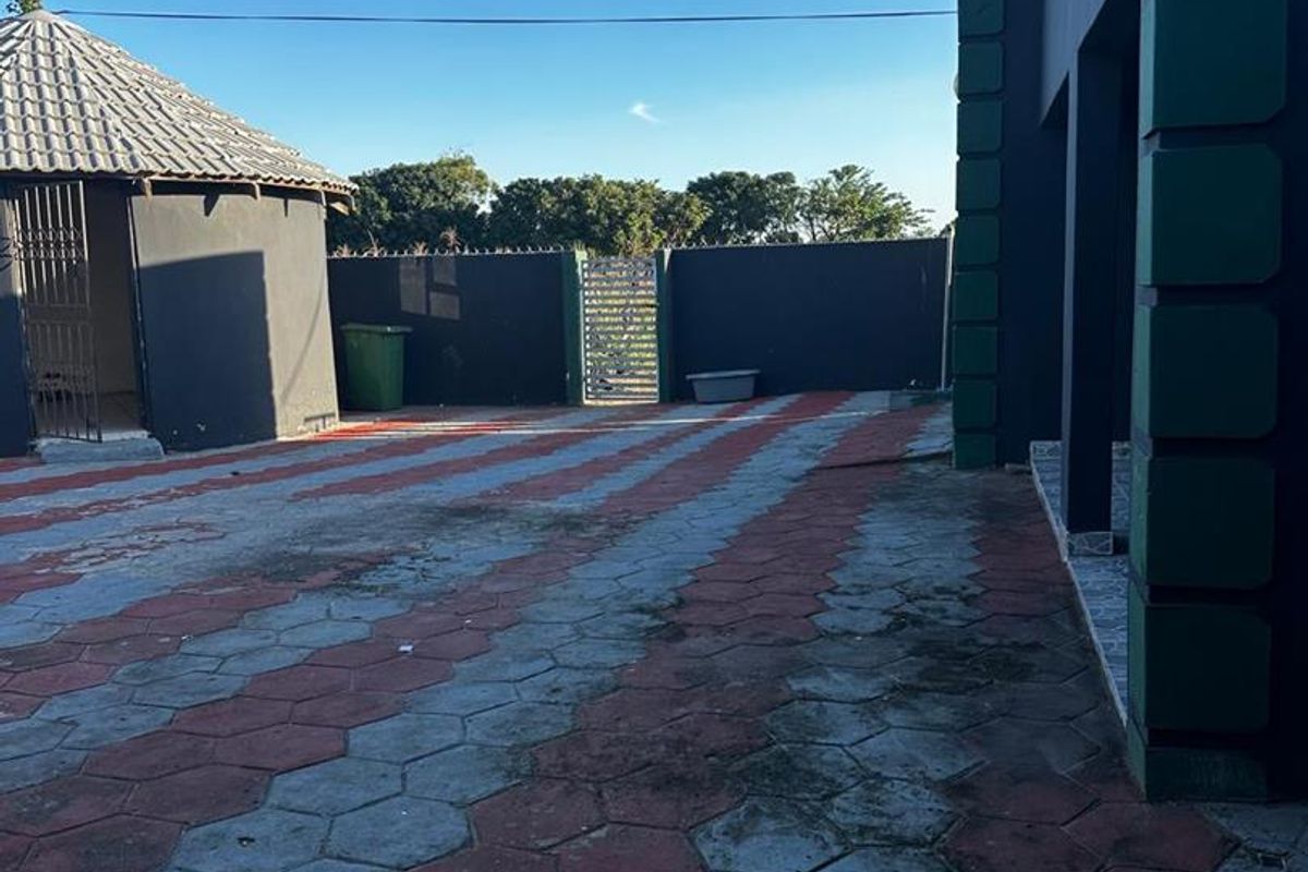 Spacious paved outdoor courtyard area featuring a detached structure and perimeter boundary walls.