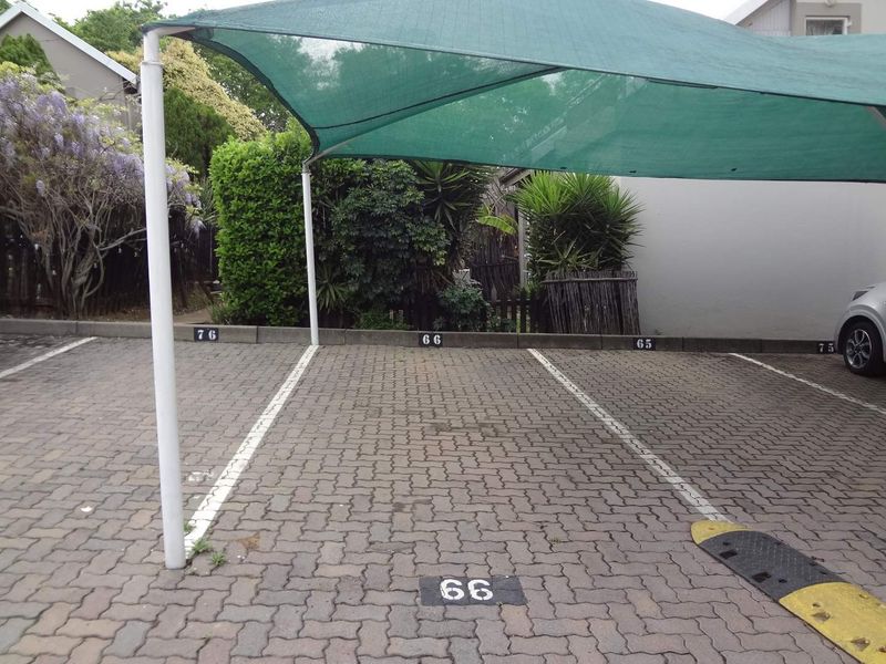 Designated parking area featuring paved surfacing, numbered bays, and a protective shade cloth carport structure.