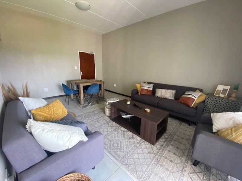 An open-plan living and dining area featuring neutral wall tones and tiled flooring, providing a versatile space for relaxation and meals.