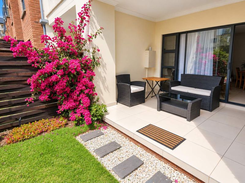 A well-maintained tiled patio area featuring a timber privacy screen, stone garden path, and direct access to the interior through sliding glass doors.