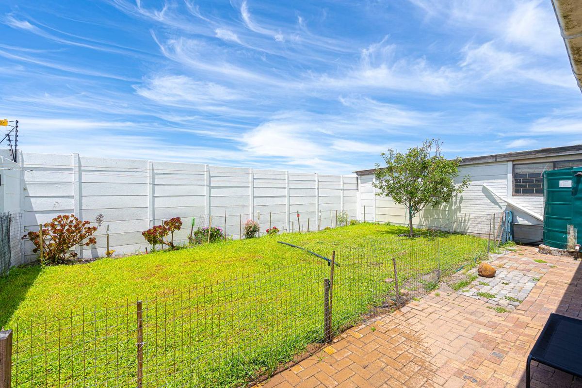 A private rear garden featuring a paved patio area, lawn, and high boundary walling, providing a secure outdoor space.