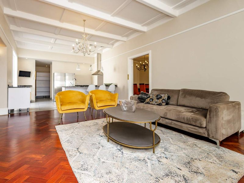 Spacious open-plan living area featuring elegant herringbone hardwood flooring, a coffered ceiling, and a modern kitchen with a central island.