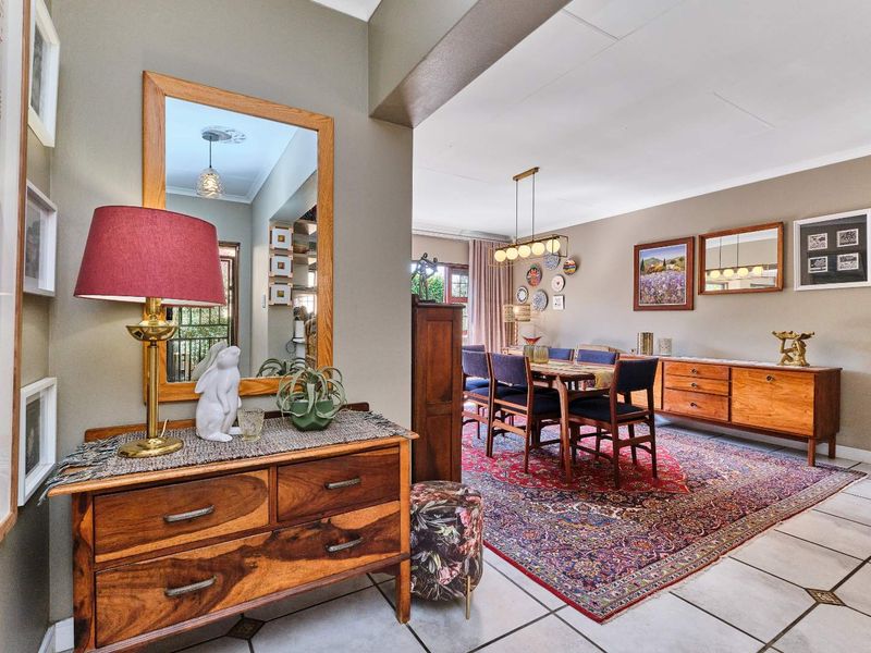 An open-plan living and dining area featuring tiled flooring, neutral wall tones, and a distinct architectural archway connecting the spaces.