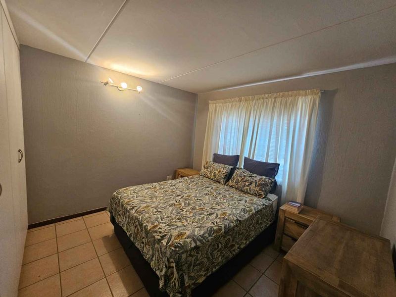A functional bedroom featuring tiled flooring, built-in cupboards, and neutral wall finishes, providing a comfortable and practical living space.