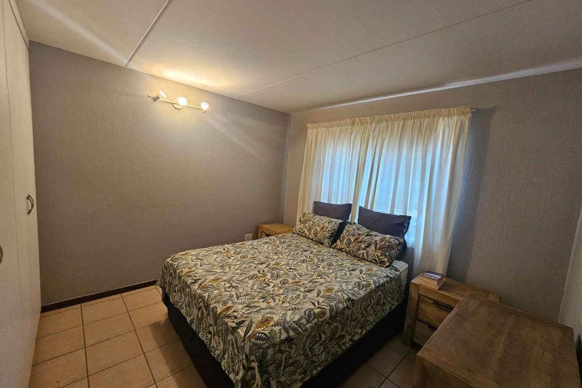 A functional bedroom featuring tiled flooring, built-in cupboards, and neutral wall finishes, providing a comfortable and practical living space.