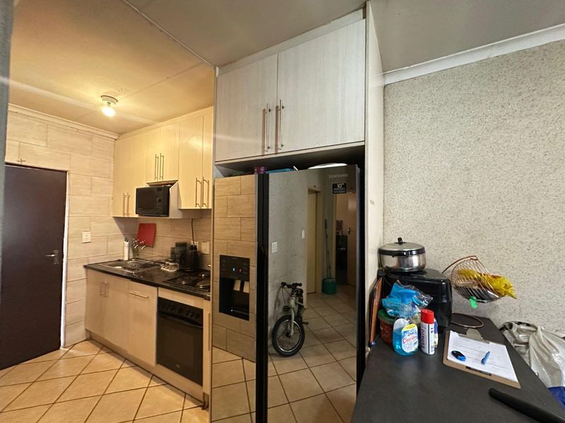 Compact kitchen featuring built-in cabinetry, black granite countertops, integrated oven and hob, and tiled flooring.