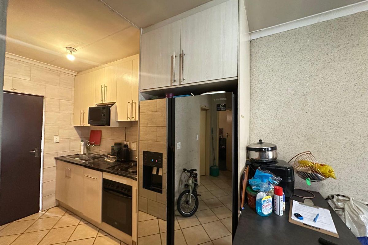 Compact kitchen featuring built-in cabinetry, black granite countertops, integrated oven and hob, and tiled flooring.