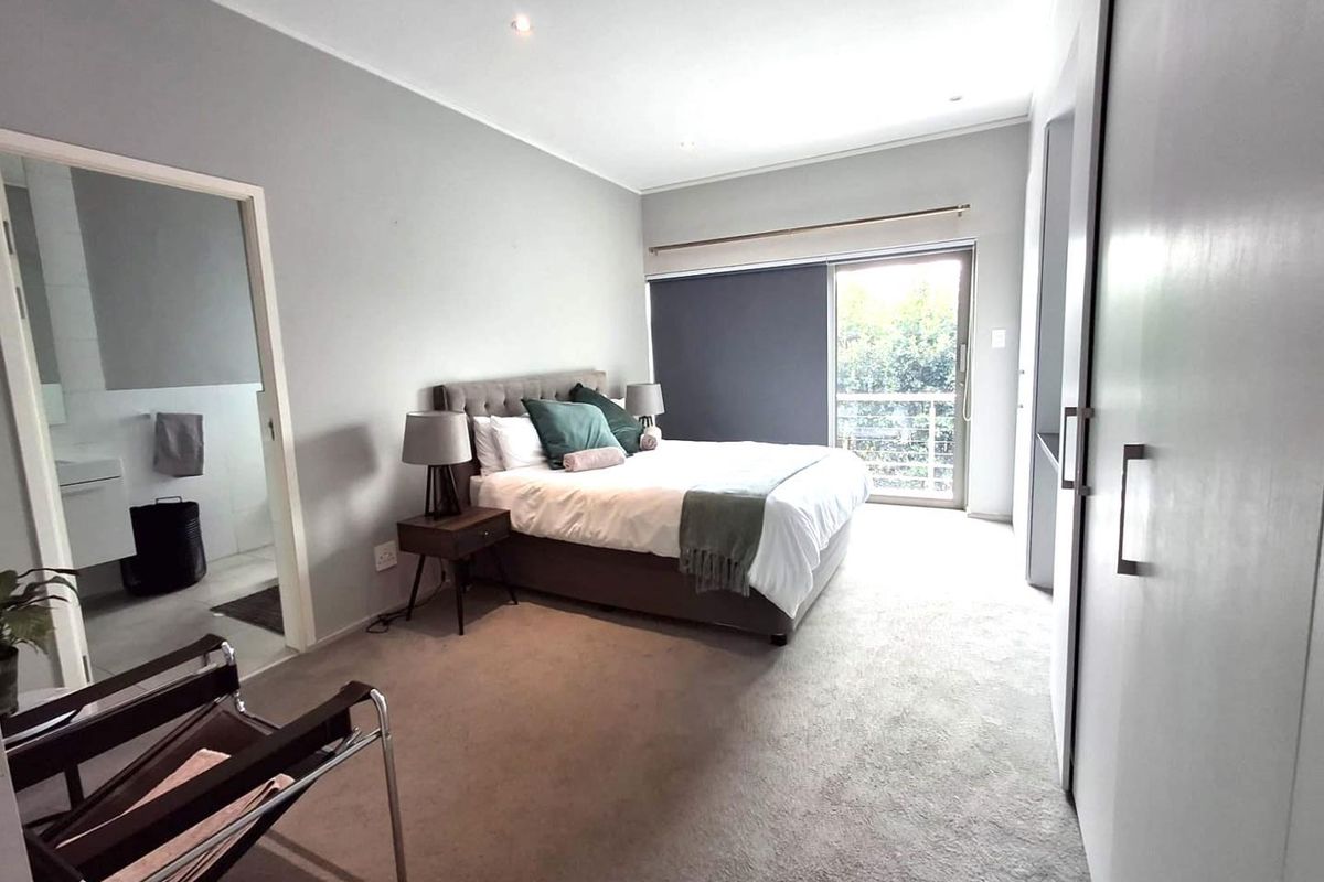 Spacious bedroom featuring neutral carpeting, built-in cupboards, recessed lighting, and direct access to an en-suite bathroom and a private balcony.