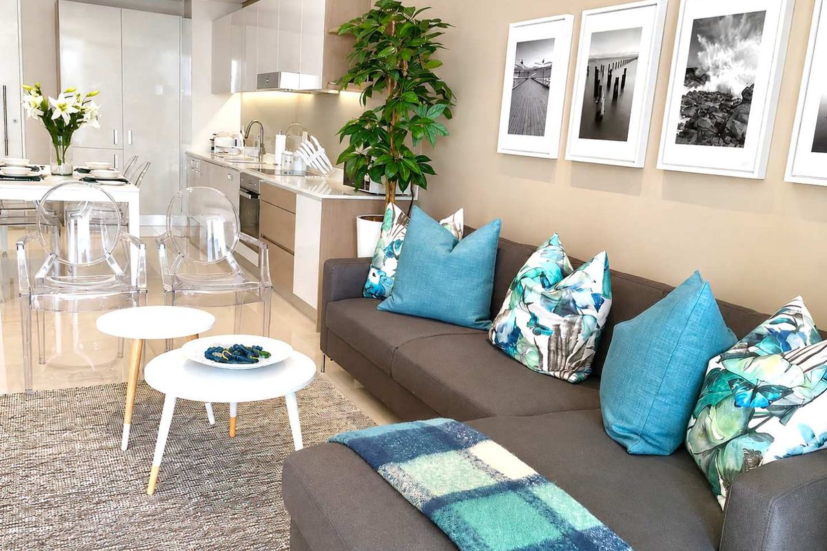 Modern open-plan living area featuring a sleek kitchen with integrated appliances, stone countertops, and neutral finishes, seamlessly flowing into the lounge space.