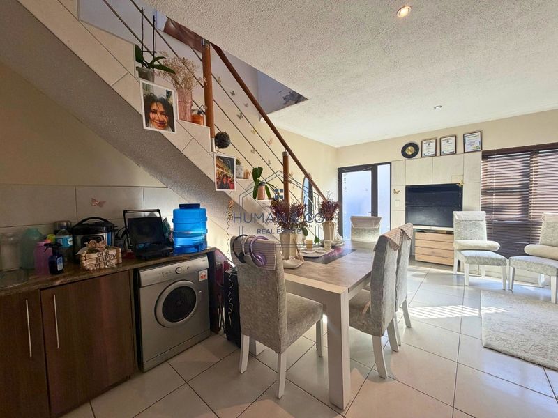 Open plan living and dining area featuring tiled floors, a staircase, and integrated cabinetry, offering a functional layout for modern townhouse living.