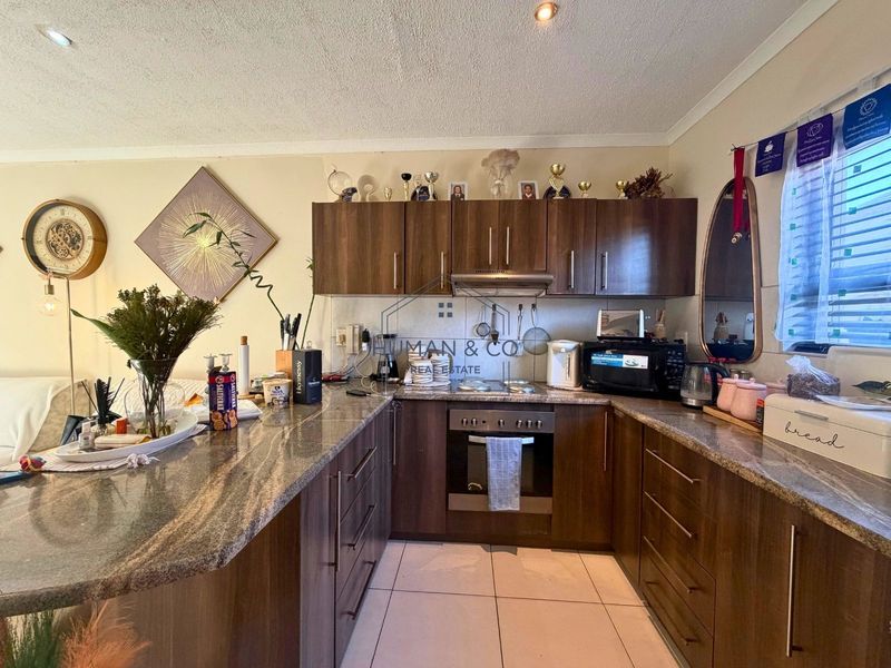 Functional kitchen featuring dark wood cabinetry, granite countertops, built-in oven, and hob, with tiled flooring and recessed lighting.