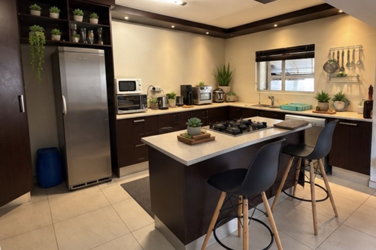 Modern kitchen featuring dark wood cabinetry, stone countertops, a central island with a gas cooktop, and recessed lighting.