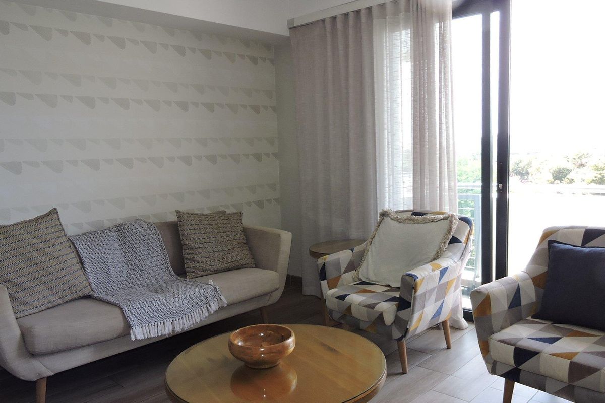 A bright living room featuring tiled flooring and a large sliding glass door providing access to an outdoor area.