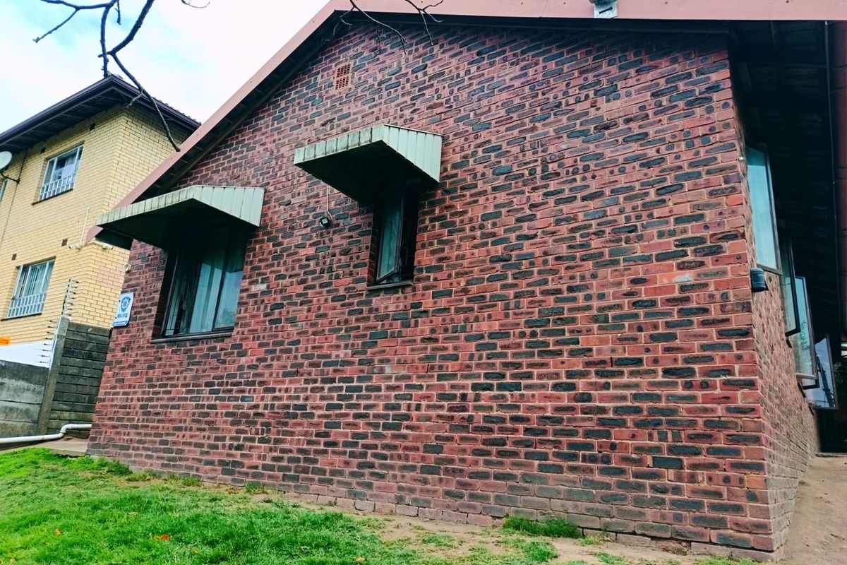A side view of the property featuring a face brick exterior, metal window awnings, and casement windows.