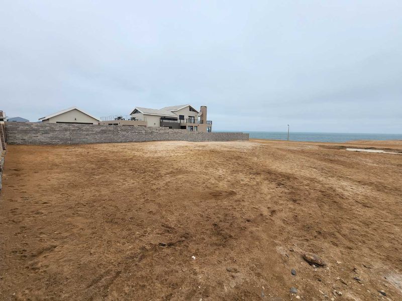 Vacant residential land plot featuring a boundary wall and coastal views, offering a prime opportunity for development in a scenic location.