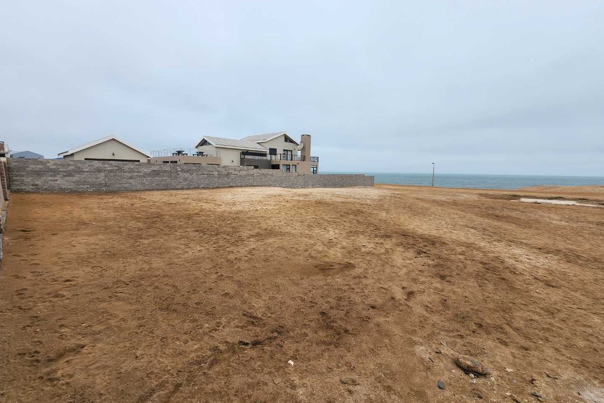Vacant residential land plot featuring a boundary wall and coastal views, offering a prime opportunity for development in a scenic location.