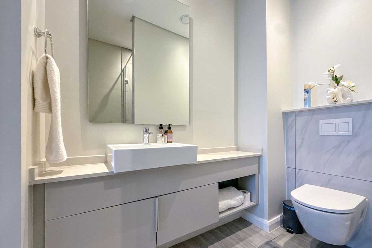 Modern bathroom featuring a wall-mounted vanity with a vessel sink, large frameless mirror, and a wall-hung toilet with concealed cistern.