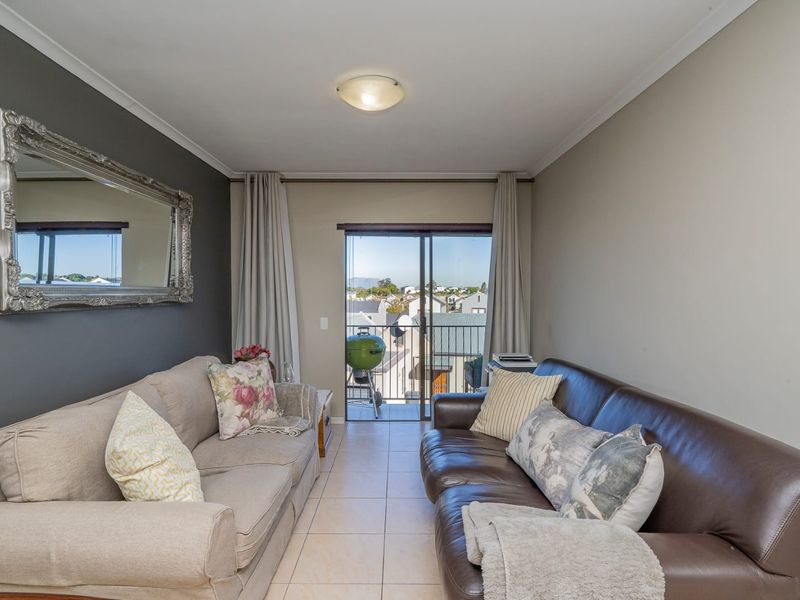 A living room featuring tiled flooring and a sliding glass door that provides access to an outdoor balcony area.