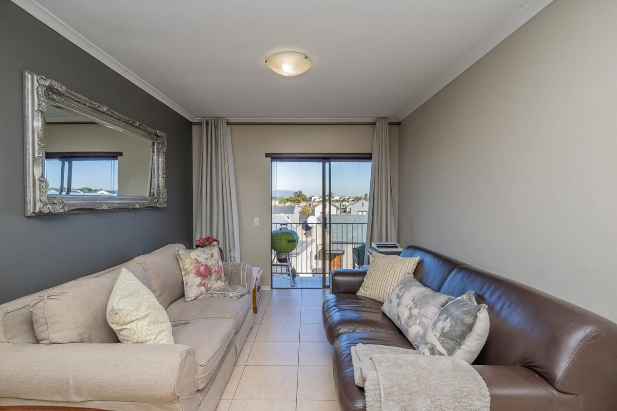 A living room featuring tiled flooring and a sliding glass door that provides access to an outdoor balcony area.