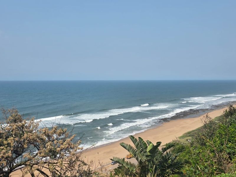 A scenic elevated view overlooking the coastline, sandy beach, and ocean waves.