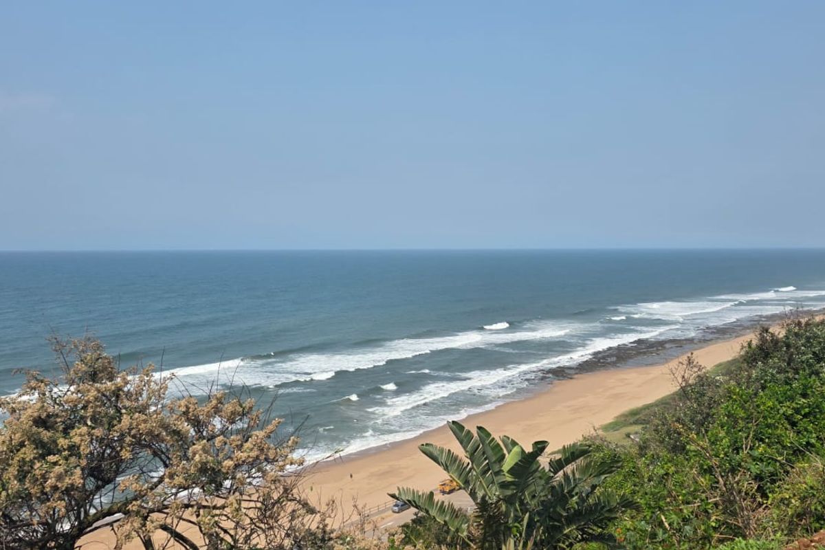 A scenic elevated view overlooking the coastline, sandy beach, and ocean waves.