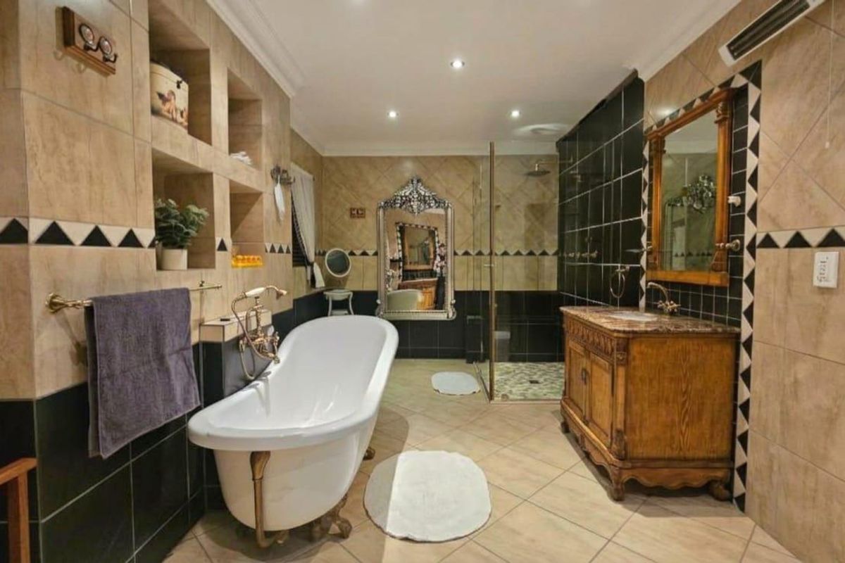Spacious bathroom featuring a classic freestanding bathtub, a separate walk-in shower, a wooden vanity cabinet, and decorative tiled wall finishes.