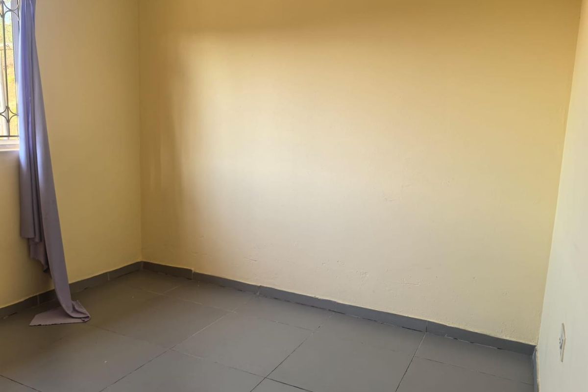 A vacant bedroom featuring tiled flooring and neutral wall finishes, providing a blank canvas for personalization.