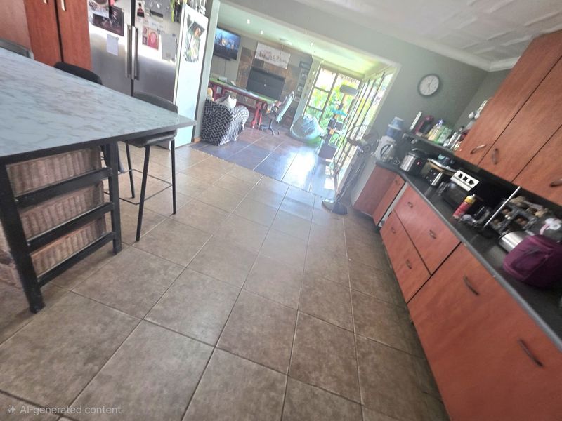 Open-plan kitchen and living area featuring tiled flooring, built-in cabinetry, and a central kitchen island, offering a functional layout for daily living.