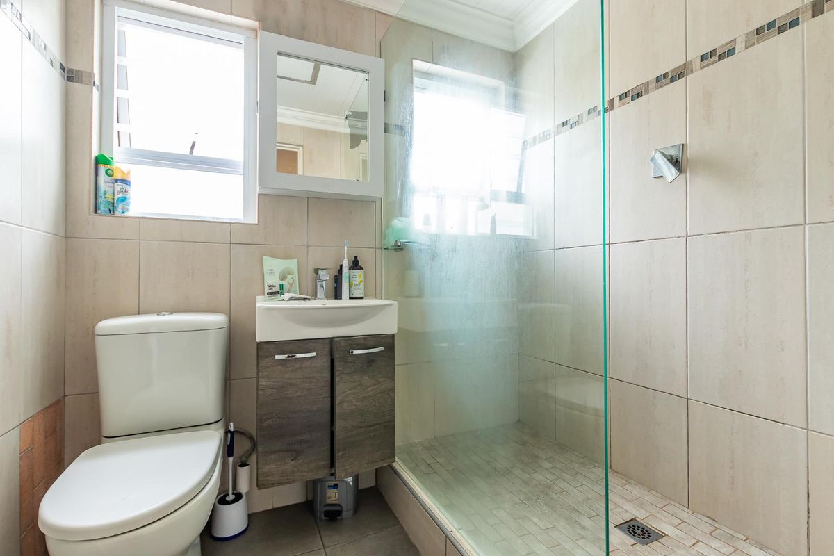 Compact bathroom featuring a walk-in shower with glass screen, wall-mounted vanity cabinet, and a modern toilet.