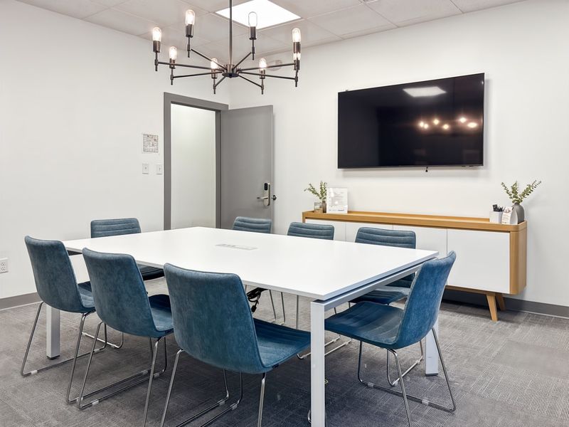 A modern, well-maintained office meeting room featuring a large conference table, suspended ceiling, and built-in storage cabinetry.