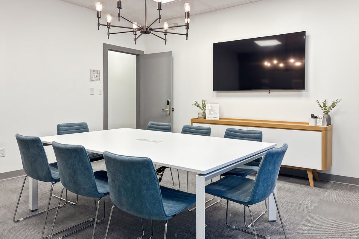 A modern, well-maintained office meeting room featuring a large conference table, suspended ceiling, and built-in storage cabinetry.