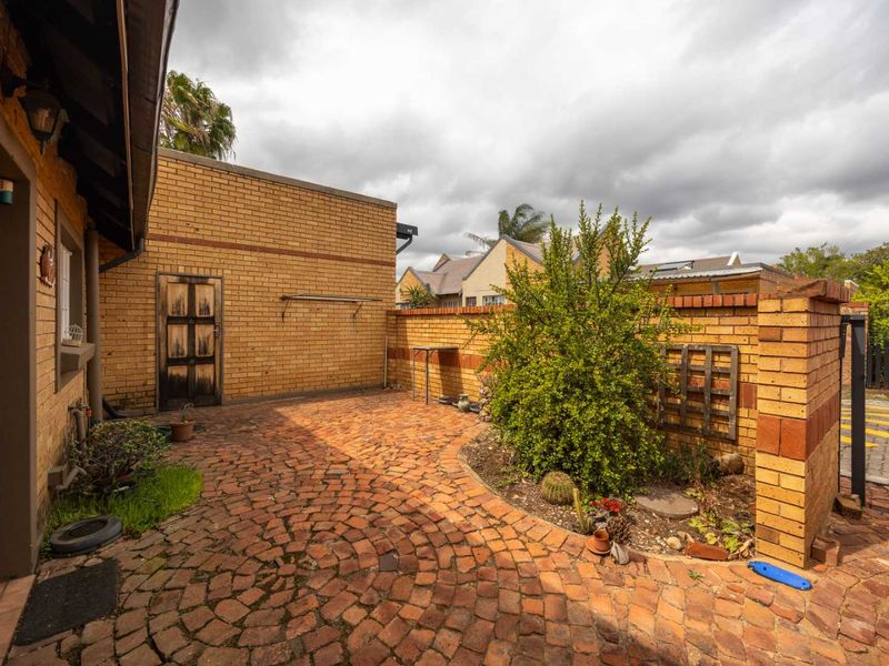 A private rear courtyard featuring brick paving, a brick boundary wall, and established garden beds, providing a functional outdoor space.