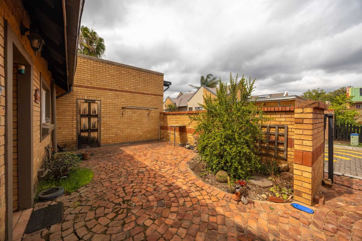 A private rear courtyard featuring brick paving, a brick boundary wall, and established garden beds, providing a functional outdoor space.