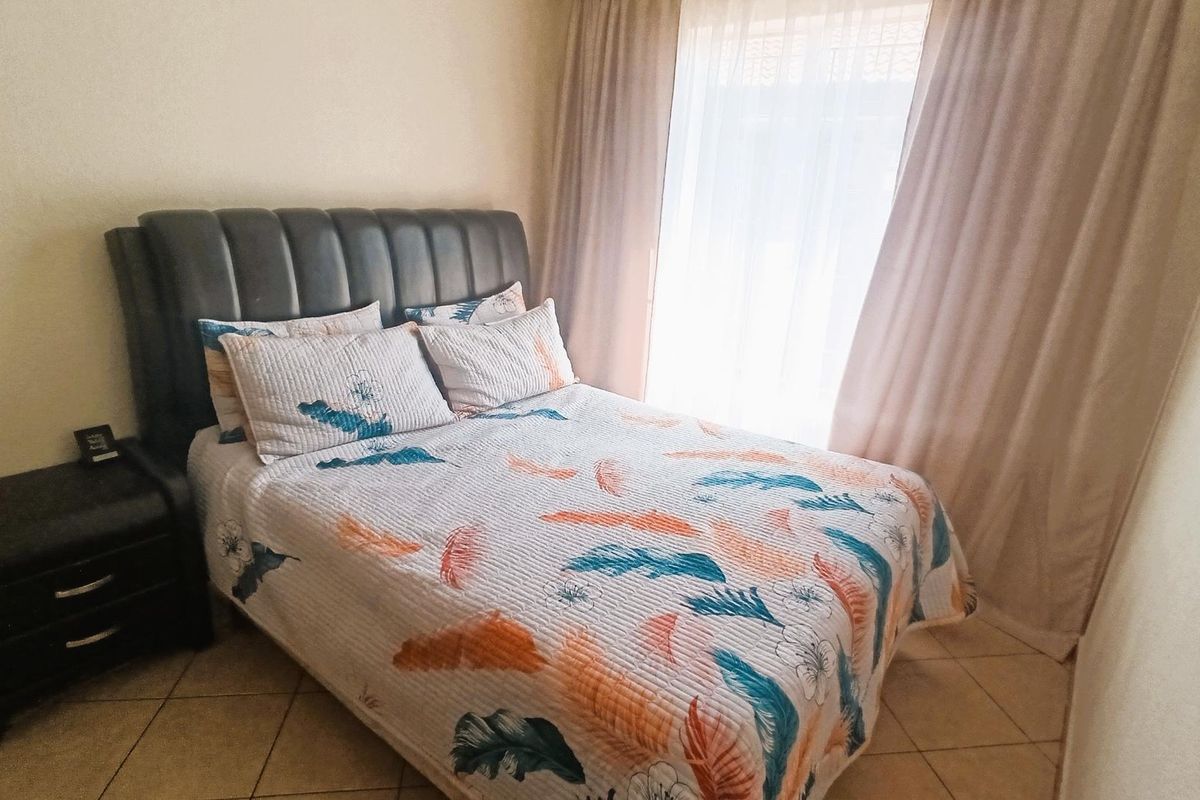 A bedroom featuring tiled flooring and a window dressed with curtains.