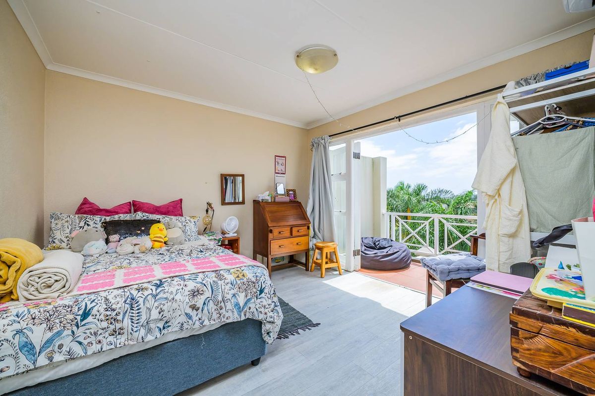 A bedroom featuring light-toned flooring and direct access to a private balcony through double doors, offering natural light and outdoor views.
