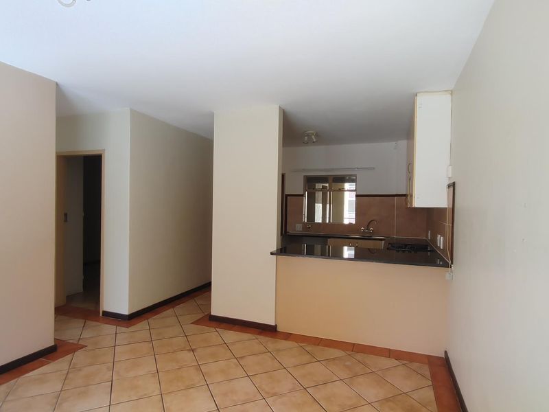 An open-plan living and kitchen area featuring ceramic tiled flooring, granite countertops, and built-in cabinetry in a neutral, well-maintained space.