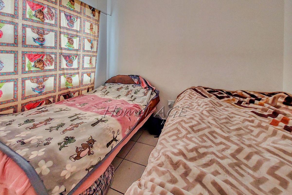 A bedroom featuring tiled flooring and a window with patterned curtains.