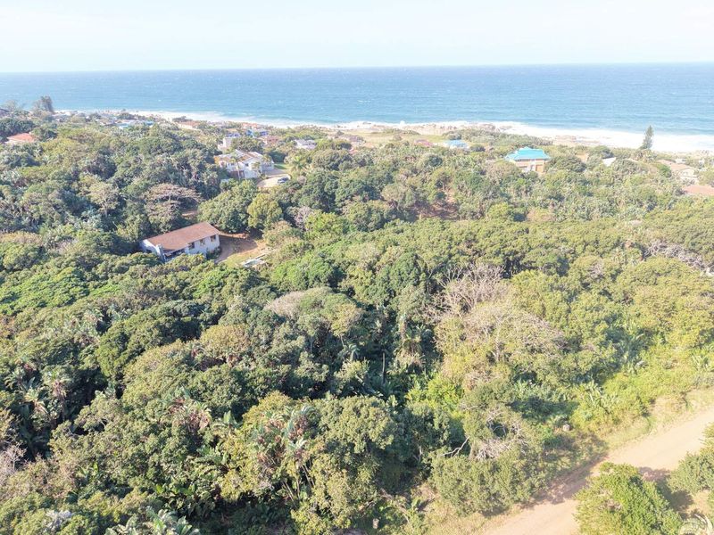 Aerial view of a coastal residential plot featuring dense indigenous vegetation and proximity to the ocean.
