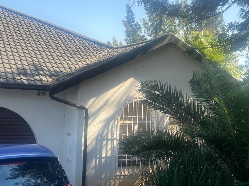 A view of the front exterior facade featuring a tiled roof, guttering, and an arched window with security bars.
