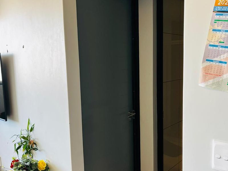 A clean hallway area featuring tiled flooring and two internal doors leading to adjacent rooms.