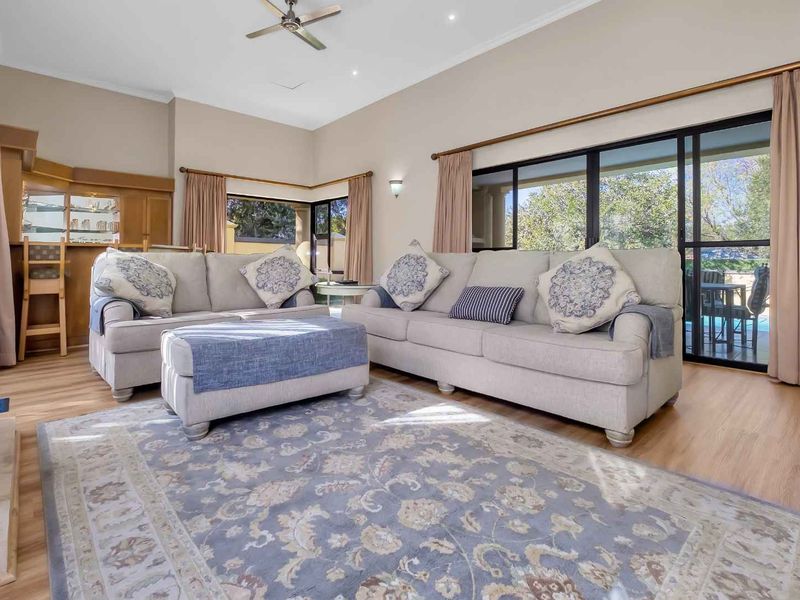Spacious living room featuring high ceilings, a built-in bar, fireplace, and large sliding glass doors providing access to the outdoor area.