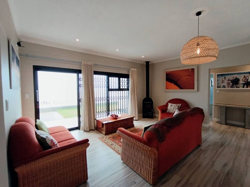 A comfortable living room featuring a freestanding fireplace, laminate flooring, and large sliding glass doors that provide access to the outdoor area.
