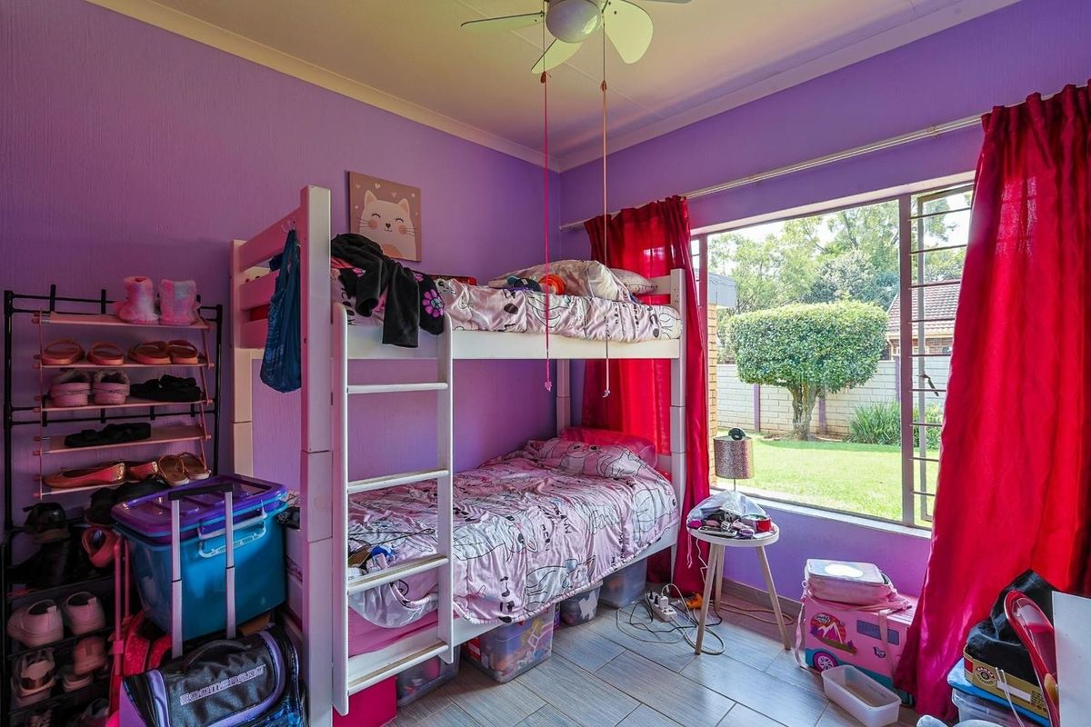 A bedroom featuring tiled flooring, a large window with garden views, and a ceiling fan.