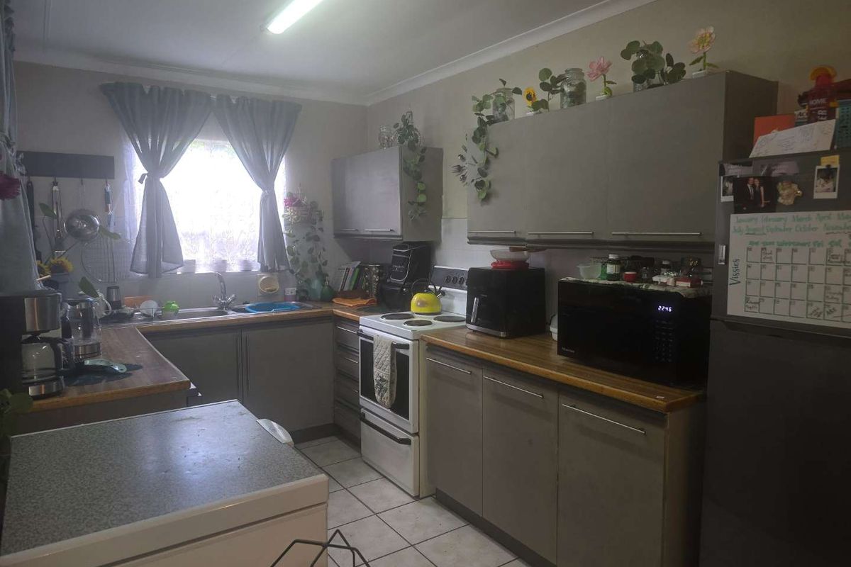 A functional kitchen featuring built-in cabinetry, laminate countertops, and a freestanding stove, offering a practical layout with potential for modern updates.
