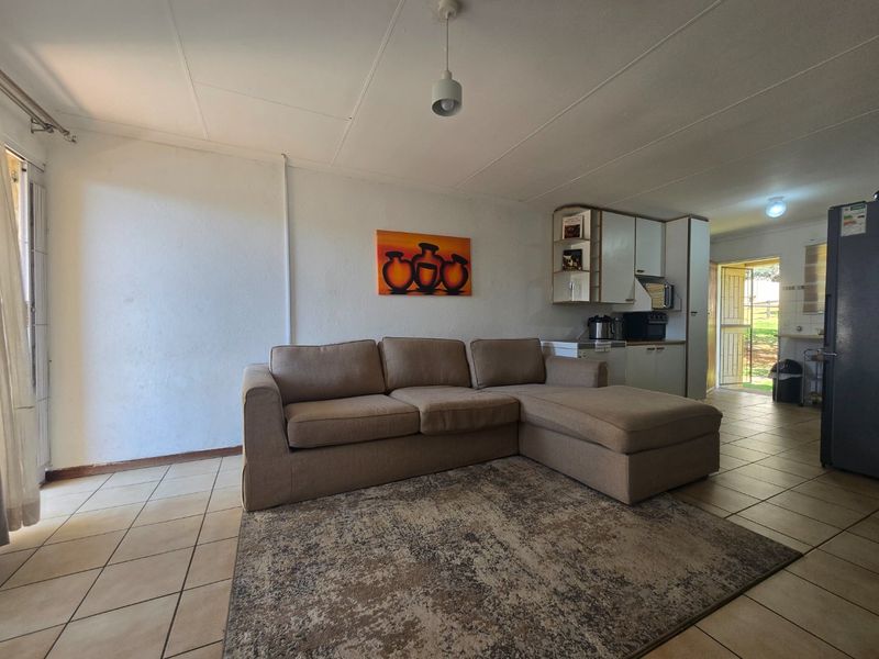 Open plan living area featuring tiled flooring, integrated kitchen cabinetry, and direct access to the exterior, offering a functional layout for daily living.