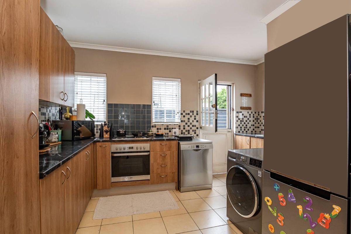 Functional kitchen featuring wood-look cabinetry, dark laminate countertops, built-in oven, hob, and direct access to the exterior.