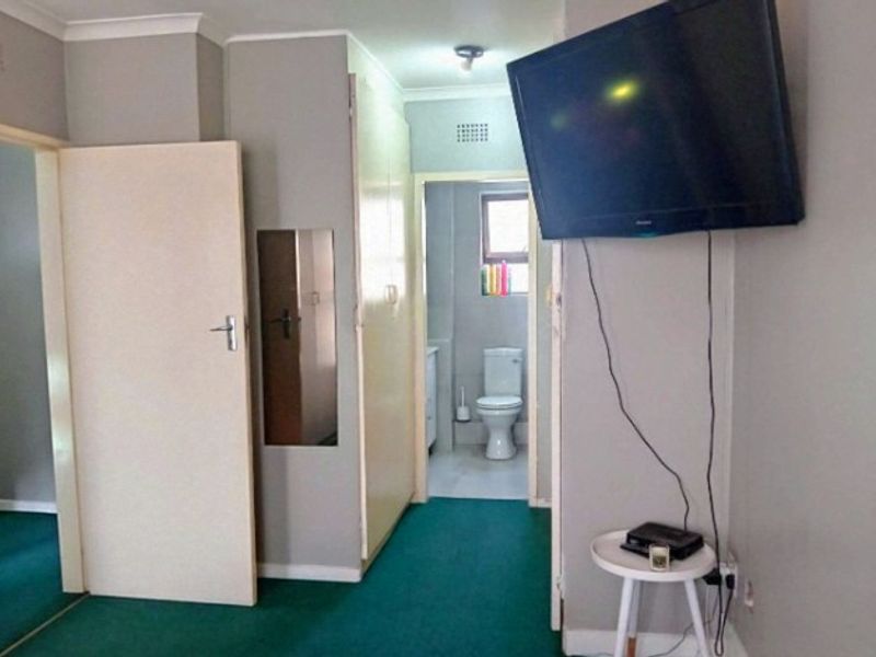 A functional hallway area featuring built-in storage cupboards and access to an adjacent bathroom.