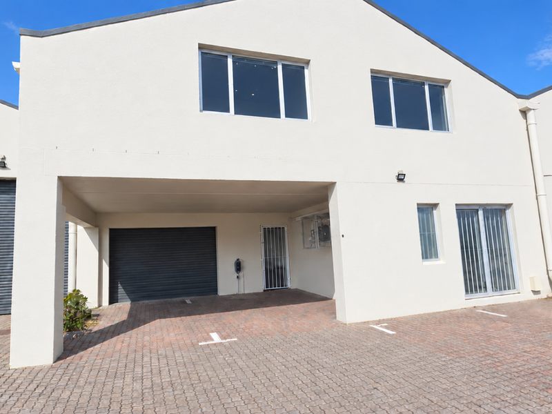 Front elevation of an industrial property featuring a paved parking area, roller shutter access, and secure entry points.