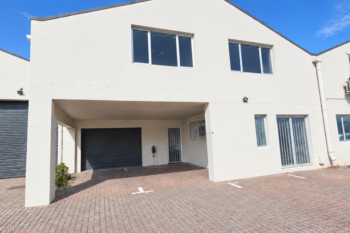Front elevation of an industrial property featuring a paved parking area, roller shutter access, and secure entry points.