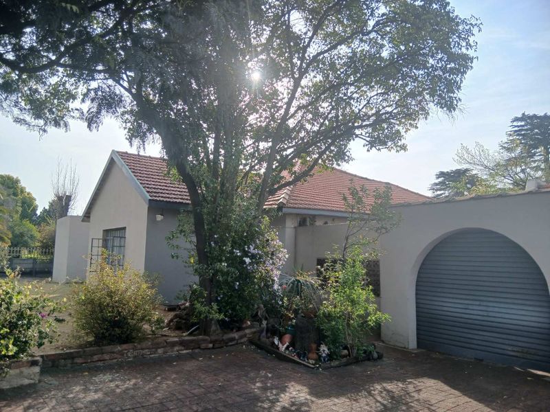 Front exterior view of the house featuring a tiled roof, arched garage entrance with a roller door, and a brick paved driveway.